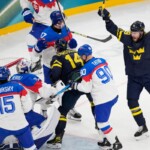 Sweden's Joel Eriksson Ek, center, scores his side's opening goal during a preliminary round match of men's ice hockey between Sweden and Slovakia at the 2026 Winter Olympics, in Milan, Italy, Saturday, Feb. 14, 2026. (AP Photo/Petr David Josek)